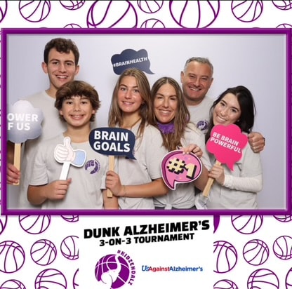 Family holding brain health awareness signs at the Dunk Alzheimer's charity basketball tournament